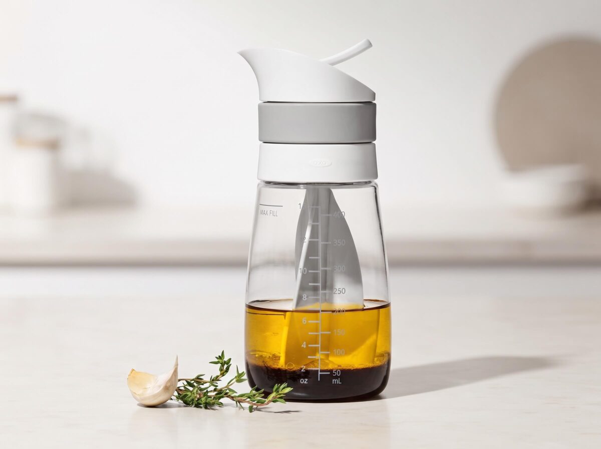 OXO Twist & Pour Salad Dressing Mixer pouring homemade dressing over a fresh salad