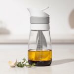 OXO Twist & Pour Salad Dressing Mixer pouring homemade dressing over a fresh salad