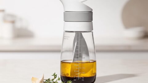 OXO Twist & Pour Salad Dressing Mixer pouring homemade dressing over a fresh salad